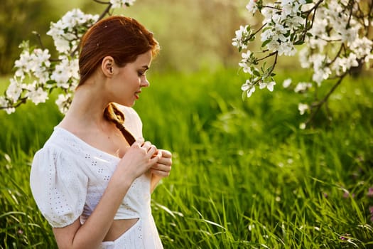 portrait of a beautiful woman looking at the flowers of an apple tree. High quality photo