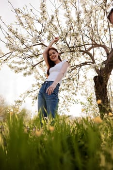 cute woman in light clothes posing next to a flowering tree in the countryside. High quality photo