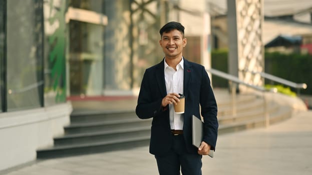 Shot of comfident young businesswoman holding takeaway coffee cup walking outdoors in business district.