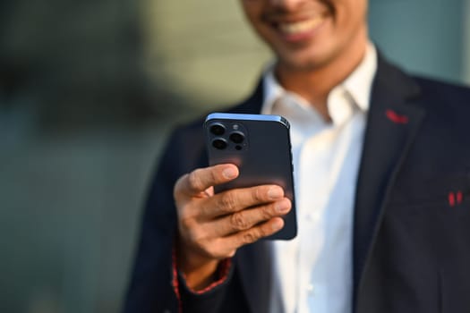 Selective focused on hand of businessman using mobile phone at outdoors. Technology, communication and people.