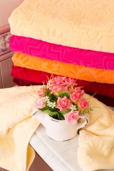 A vertical shot of folded colorful bamboo towels on a bathroom cabinet with a bouquet decoration