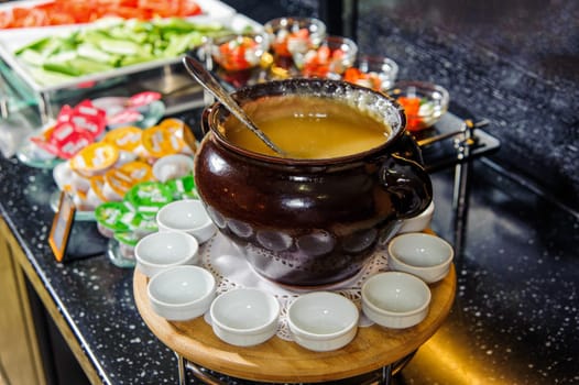 A bowl of soup puree on a buffet table with small bowls around