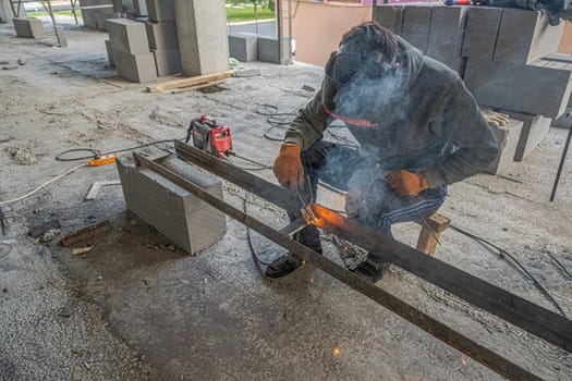 A working welder makes a metal structure in a new building infrastructure