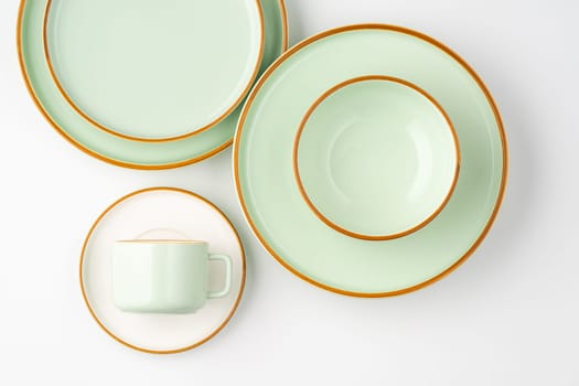A set of white and pastel green ceramic tableware with orange outlines. Top view