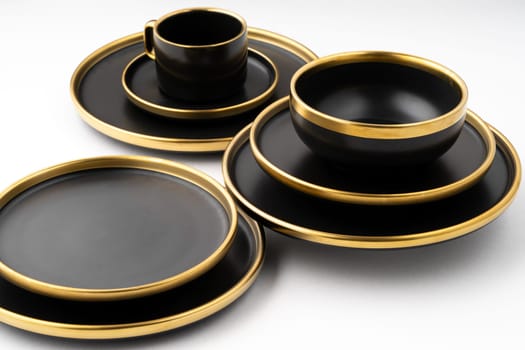 A set of black and golden ceramic plates and cup on a white background