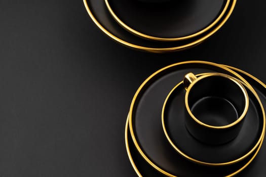 A set of black and golden ceramic plates and cup on a black background