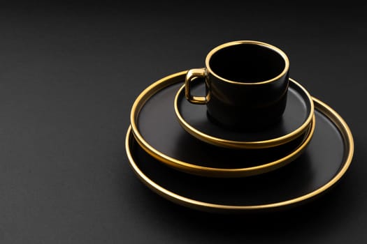 A set of black and golden ceramic plates and cup on a black background