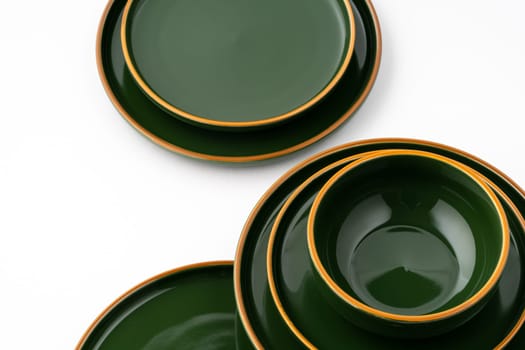 A set of green ceramic plates and bowl on a white background