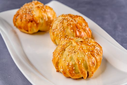 The meatballs wrapped in puff pastry covered with sesame seeds on a white plate