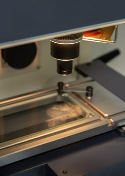 A vertical closeup shot of an illuminated microscope at a medical production warehouse