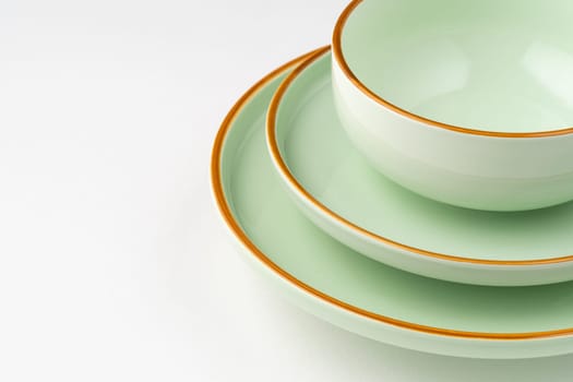 A set of pastel green ceramic tableware with orange outlines. Close-up