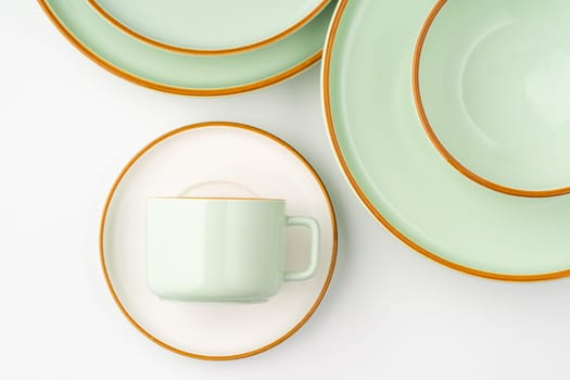 A set of white and pastel green ceramic tableware with orange outlines