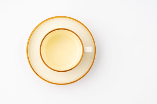 A set of white and brown ceramic plate and cup on a white background. Top view