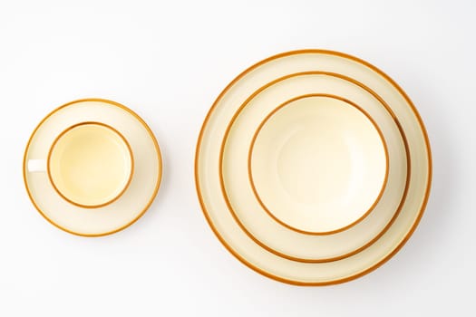 A set of white and brown ceramic plate and cup on a white background. Top view