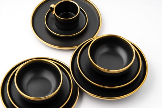 A set of black and golden ceramic plates and cup on a white background