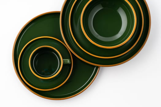 A set of dark green ceramic tableware with orange outlines on a white background