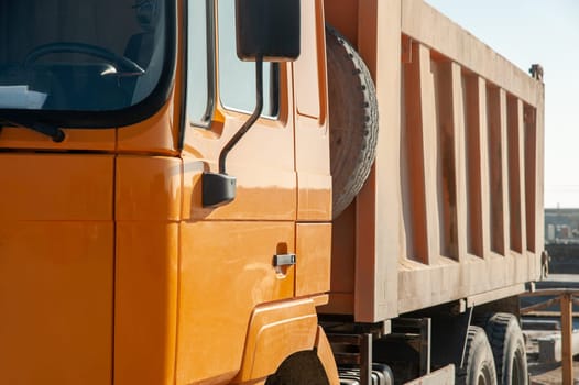 A closeup of an orange dumper truck in an construction area