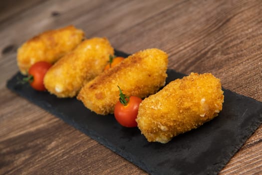 Homemade traditional Spanish croquettes or croquetas on a black plate with fork, Tapas food, High quality photo