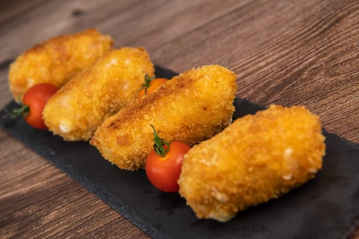 Homemade traditional Spanish croquettes or croquetas on a black plate with fork, Tapas food, High quality photo