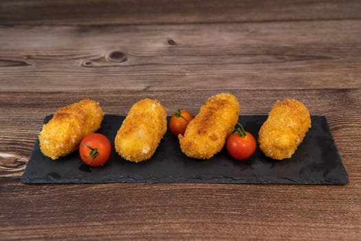 Homemade traditional Spanish croquettes or croquetas on a black plate with fork, Tapas food, High quality photo