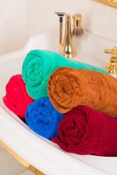 A vertical shot of rolled colorful bamboo towels in a sink in a bathroom