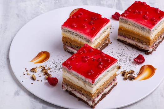 An appetizing dessert with slices of cakes with raspberry and nuts