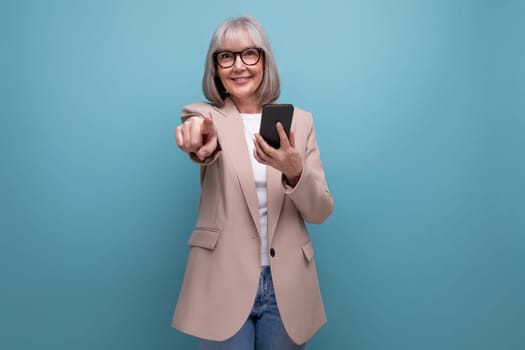 mature woman in a stylish image with a smartphone in her hands on a studio background with copy space.