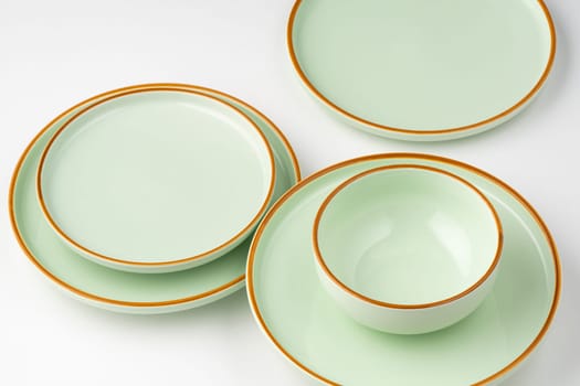 A set of pastel green ceramic tableware with orange outlines