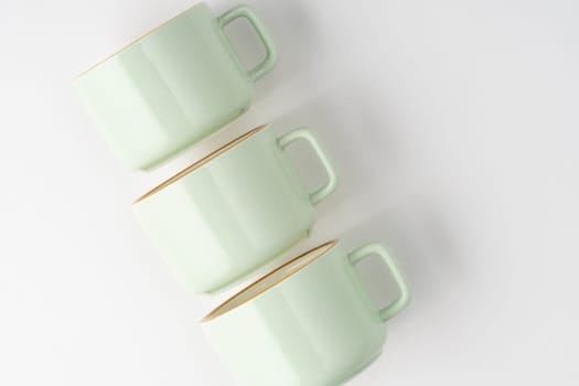 A set of white and pastel green ceramic teacups with orange outlines