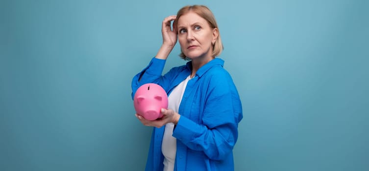 adult woman with a piggy bank of money on a blue background with copy space.