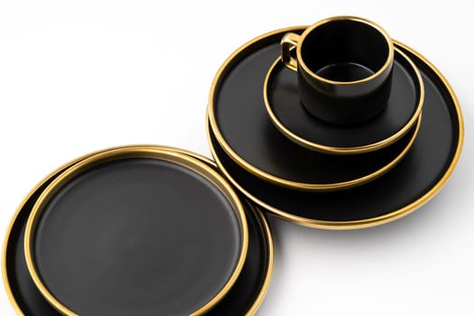 A set of black and golden ceramic plates and cup on a white background