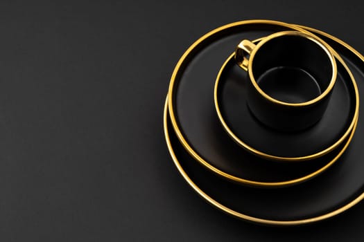 A set of black and golden ceramic plates and cup on a black background