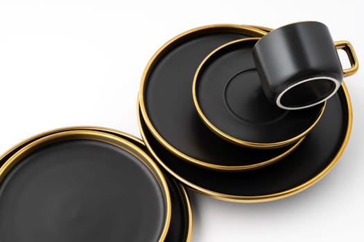 A set of black and golden ceramic plates and cup on a white background