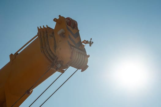 A closeup of a track crane tower against a sunny sky