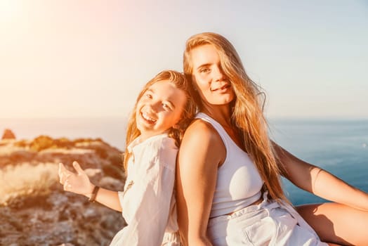 Close up portrait of mom and her teenage daughter hugging and smiling together over sunset sea view. Beautiful woman relaxing with her child.