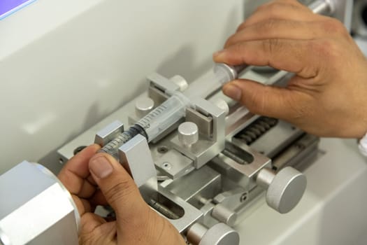 A closeup shot of hands working on a machine in a medical production warehouse for syringes