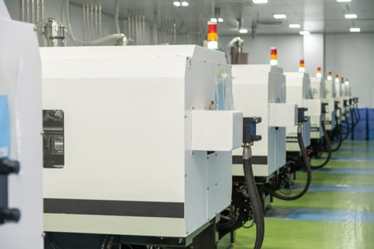 A molding machine from behind with hanging hosepipes in a factory for the production of medical syringes and droppers