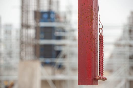 A selective focus of a hanging rail with a hammer for ringing lunch break or the end of the working day at construction with blurred background