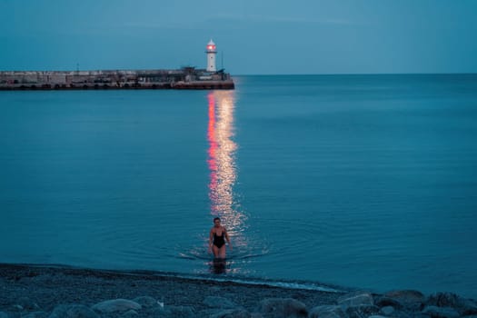 Woman The full moon rises to the lighthouse, the lunar path along the sea leads to the woman