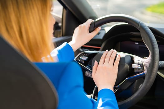 Back view of woman driving car and press down vehicle horn in blue suit