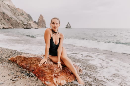 Side view a Young beautiful sensual woman in a mint long dress posing on a volcanic rock high above the sea during sunset. Girl on the nature on overcast sky background. Fashion photo