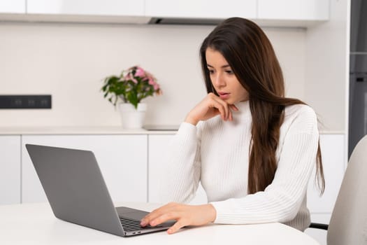 Sad businesswoman sitting at desktop working on laptop and holding hand. Hard working day concept.