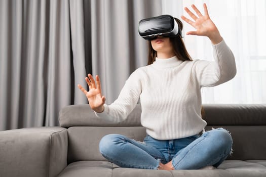 Young woman in vr glasses, playing video games and touching something in the air. Playing games at home in the living room