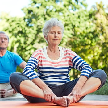 Feel the benefits of exercising. a senior couple doing yoga together outdoors