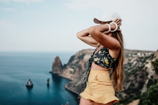 Woman travel sea. Happy tourist taking picture outdoors for memories. Woman traveler looks at the edge of the cliff on the sea bay of mountains, sharing travel adventure journey.