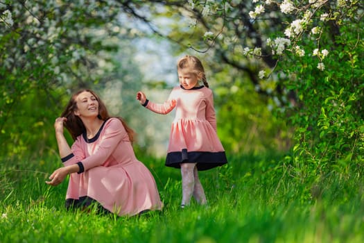 mother and daughter in nature in identical dresses