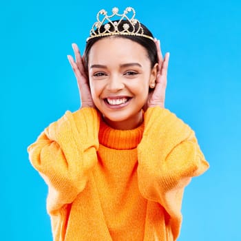 Excited, crown and portrait of woman in studio for celebration, princess and party. Smile, beauty and fashion with female and tiara on blue background for achievement, winner and prom event.