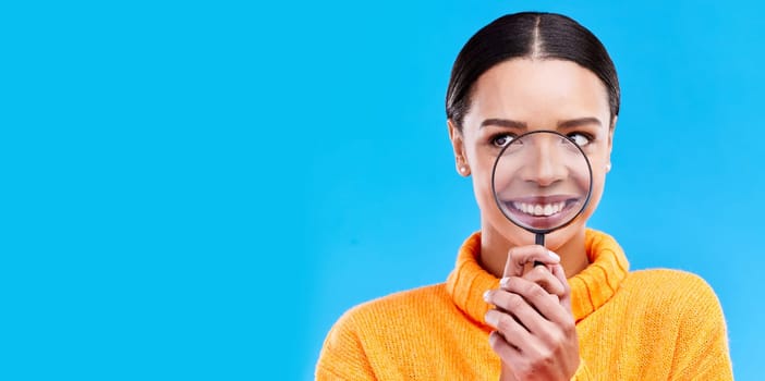 Happy, smile and woman with magnifying glass in studio for zoom on her mouth for dental health. Happiness, excited and female model from Brazil with magnifier isolated by blue background with mockup
