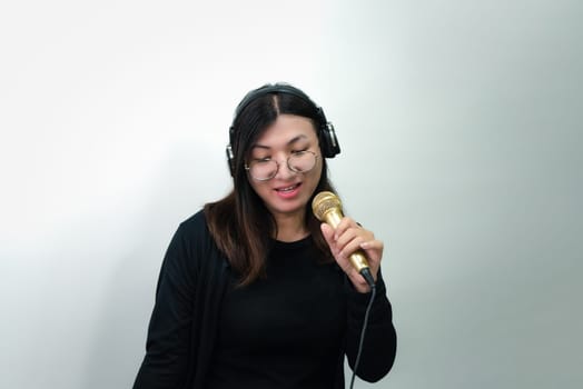 Beautiful asian woman (LGBTQ) is a singer. She enjoying sing a song or karaoke in music studio with microphone condenser and headphones for fun or voice creative