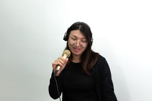 Beautiful asian woman (LGBTQ) is a singer. She enjoying sing a song or karaoke in music studio with microphone condenser and headphones for fun or voice creative